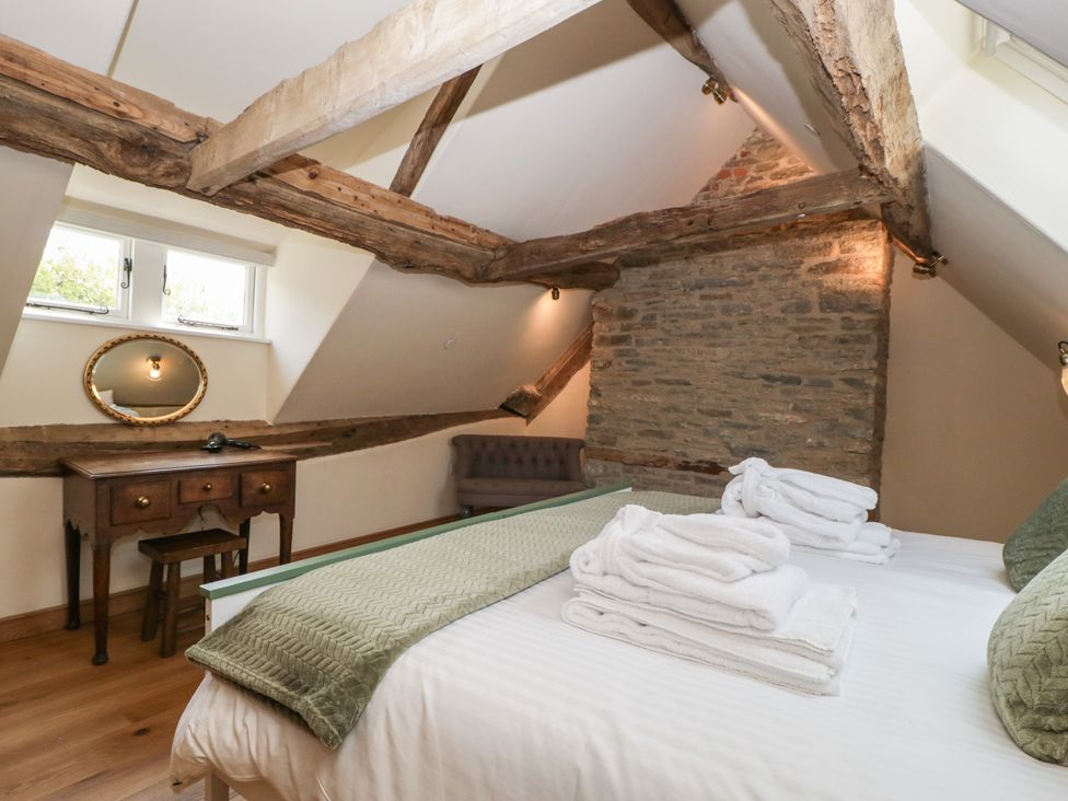 A bedroom with a bed and desk at Evenjobb Court Farmhouse Evenjobb near Presteigne