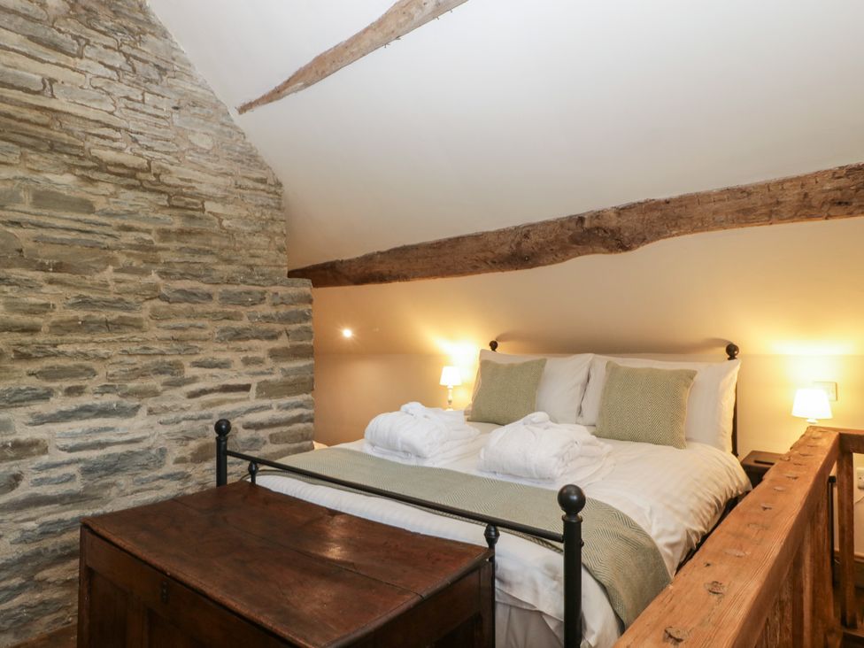 A bedroom with a bed and stone wall at Evenjobb Court Farmhouse near Presteigne