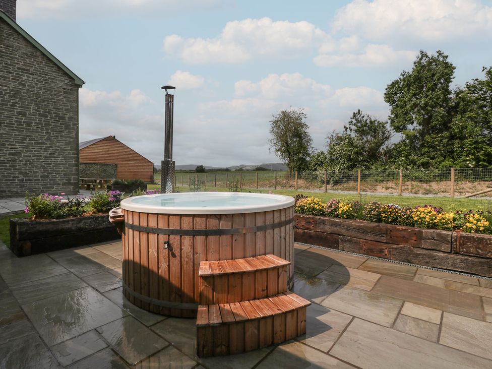 An outdoor space with a hot tub and flower bed at Evenjobb Court Farmhouse near Presteigne