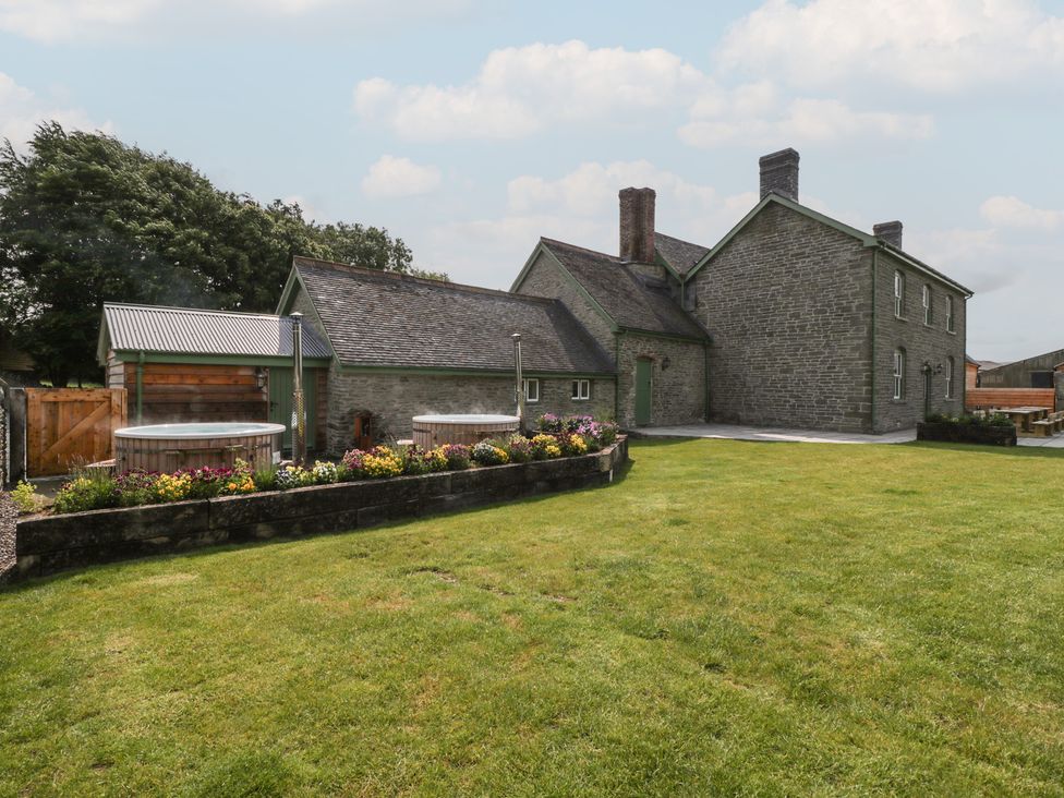 An outdoor courtyard with a house and hot tub at Evenjobb Court Farmhouse Evenjobb near Presteigne