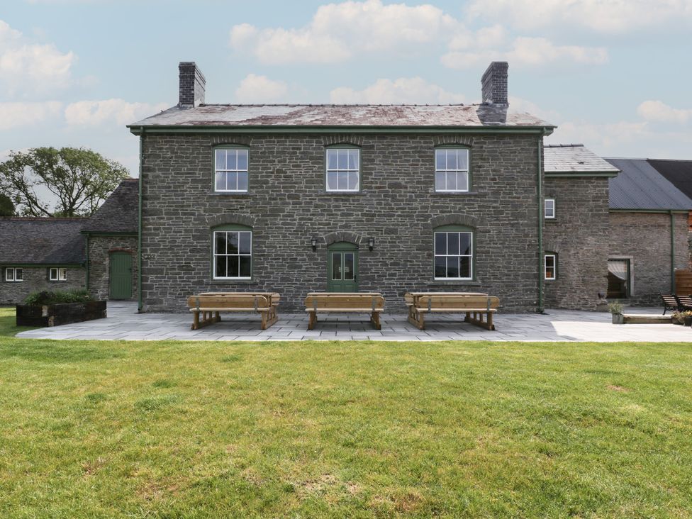 An outdoor view of a stone house with benches at Evenjobb Court Farmhouse Evenjobb near Presteigne