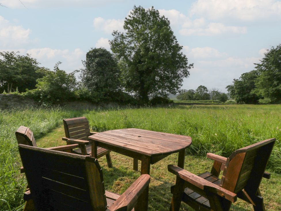 A wooden table and chairs in an outdoor area at Evenjobb Court Farmhouse near Presteigne