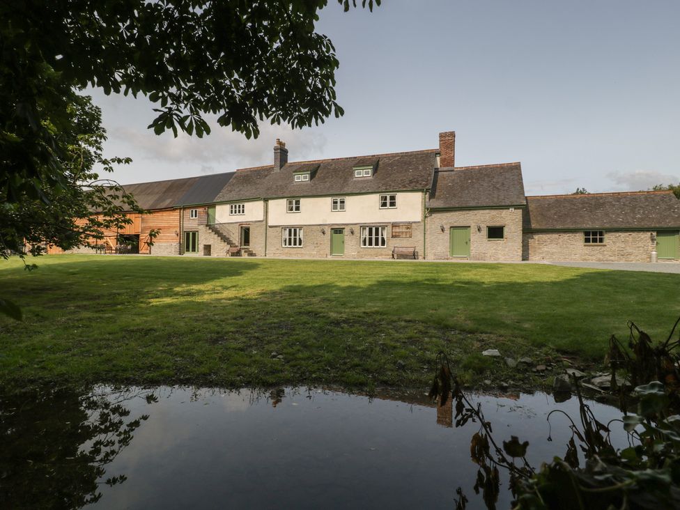 A building surrounded by grass and trees at Evenjobb Court Farmhouse Evenjobb near Presteigne