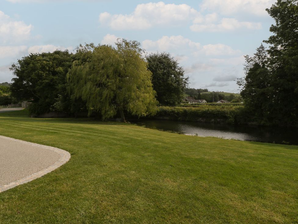 An outdoor area with grass and trees near a river at Evenjobb Court Farmhouse Evenjobb near Presteigne