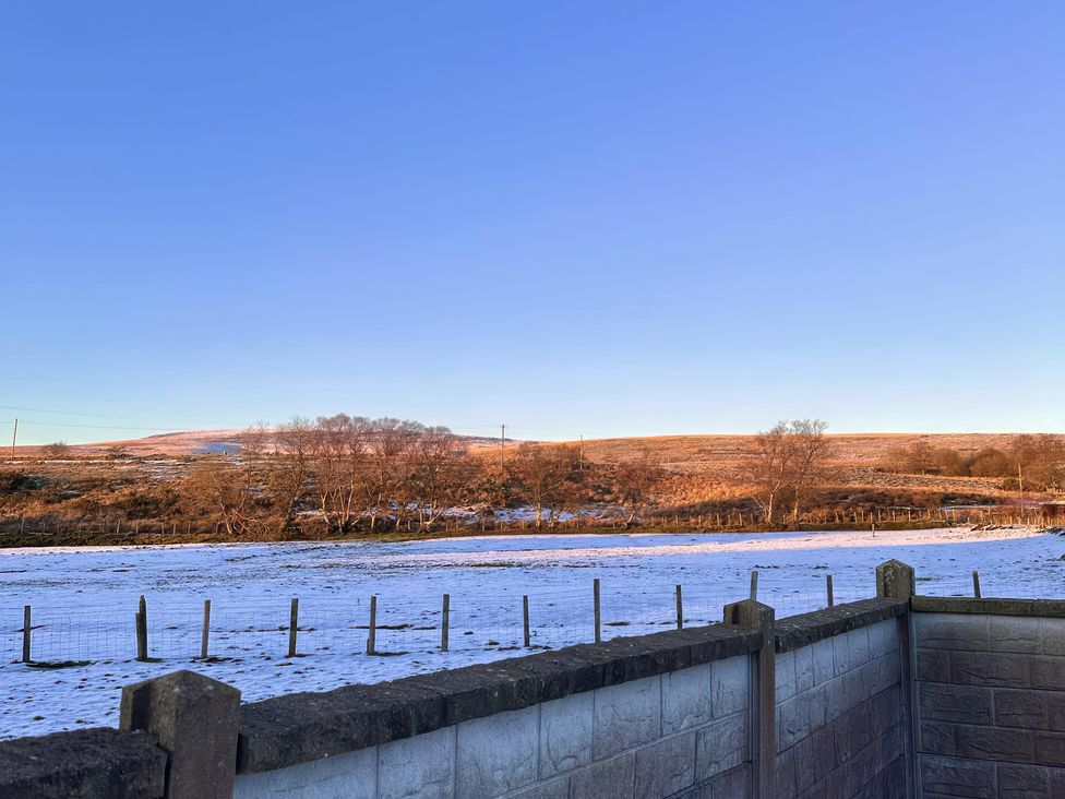 A field with snow and trees at Ty Drws Nesaf in Cwmllynfell