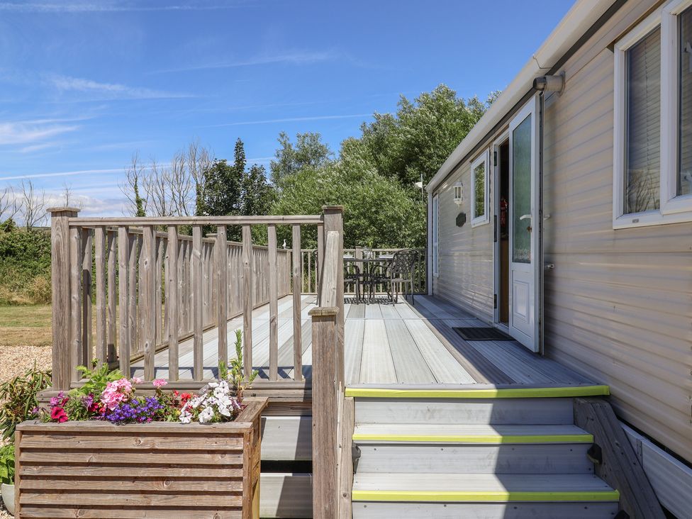An outdoor area with decking, steps, a door, and a table with chairs at The Hideaway in Portesham