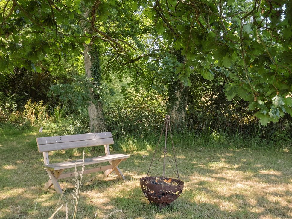 A garden with a bench and a fire pit at The Hideaway in Portesham