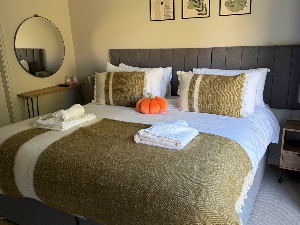 A bedroom with a bed, pillows, towels, and a mirror at The Annexe in Bridlington
