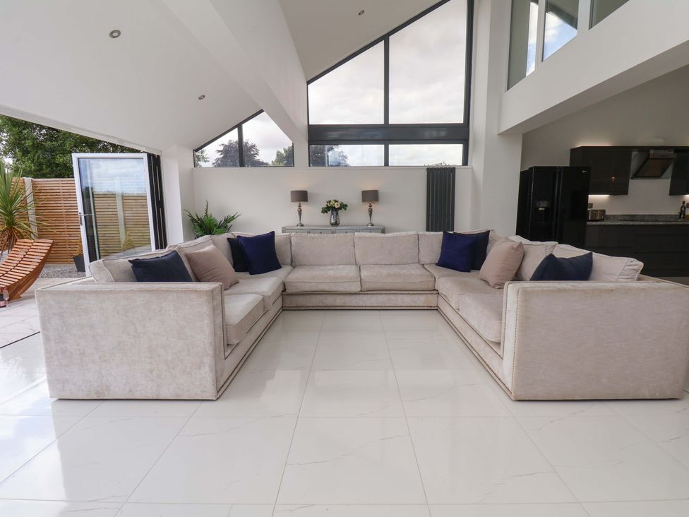 A living room with a large sofa and windows at Mill Cottage in Walkington