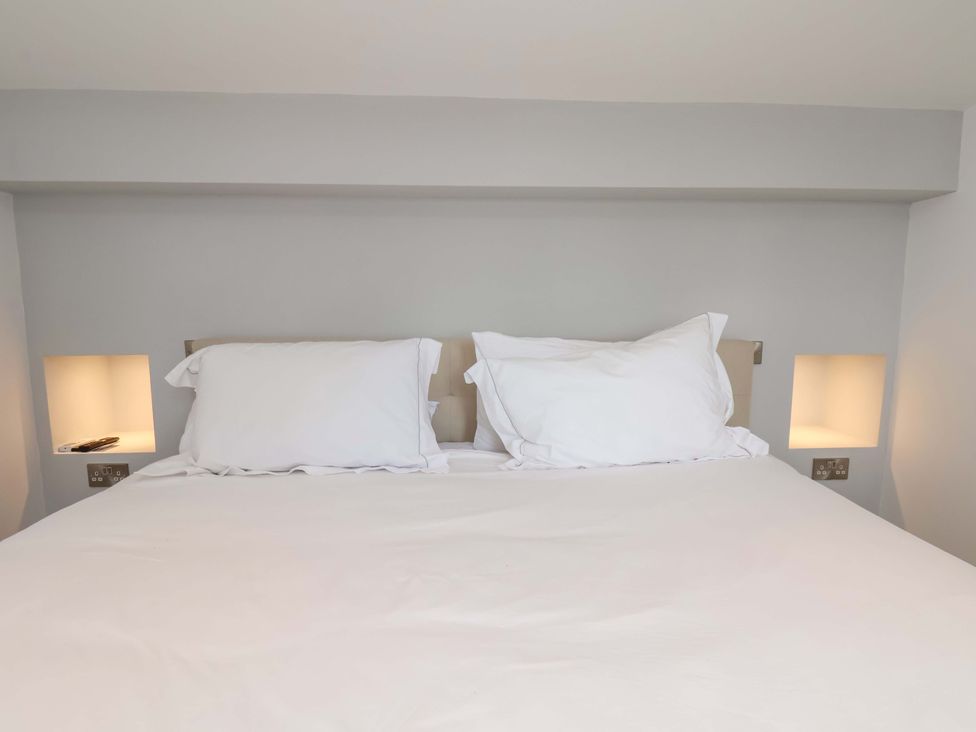 A bed with pillows and bedside lights at Mill Cottage Walkington