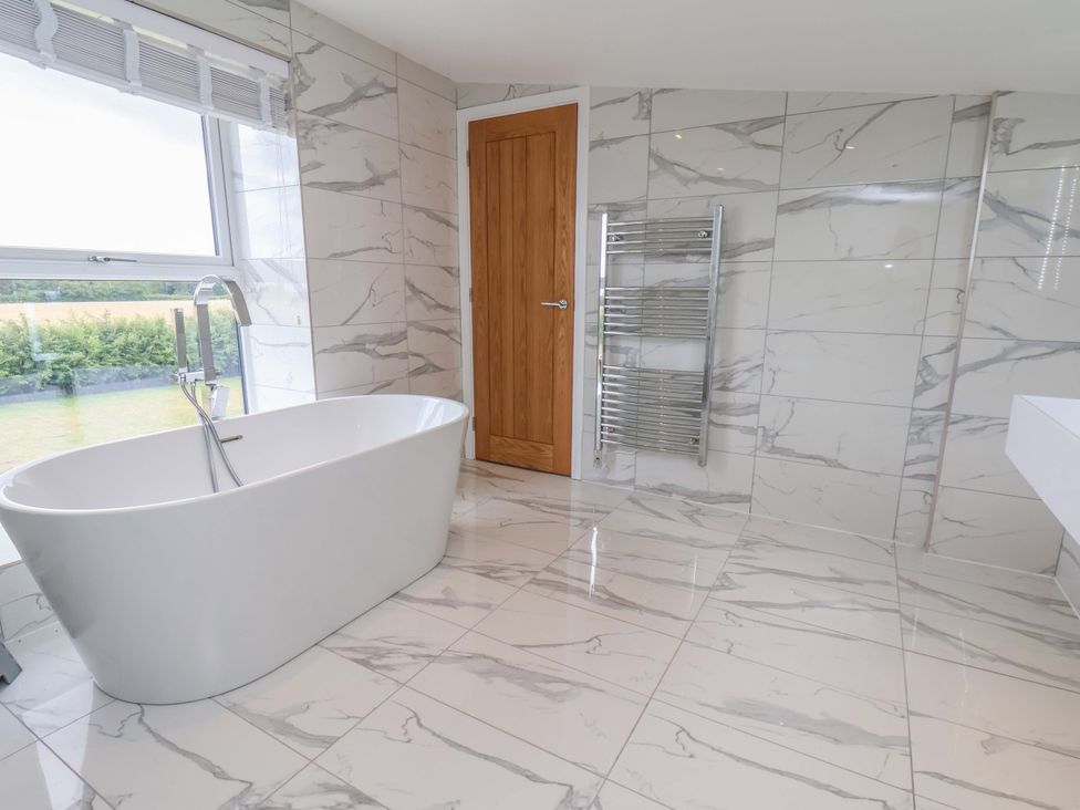 A bathroom with a bathtub and towel rail at Mill Cottage in Walkington