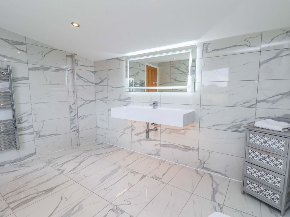A bathroom with a sink, mirror and towel radiator at Mill Cottage in Walkington