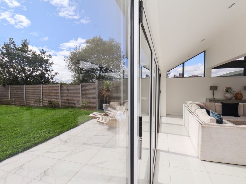 A living room with glass doors opening to a lawn at Meadow View Beverley near Walkington