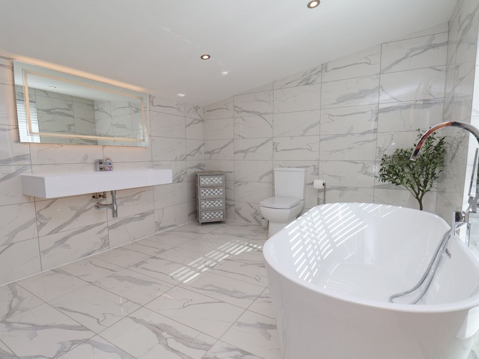 A bathroom with a bathtub, toilet, sink, and storage unit at Meadow View Beverley near Walkington