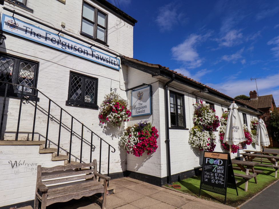 An outdoor area of The Ferguson Fawsitt pub with a bench and flowers in Beverley near Walkington