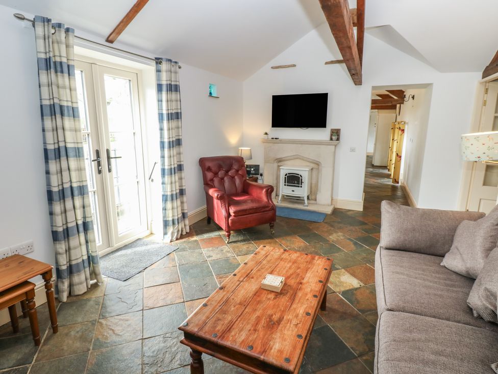 A living room with a sofa and armchair at Rainbow Cottage in Kirkby Stephen