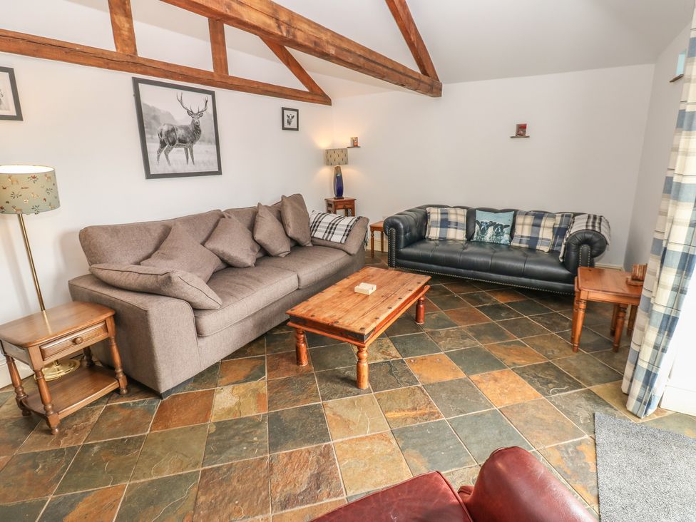 A living room with sofas and a table at Rainbow Cottage in Kirkby Stephen