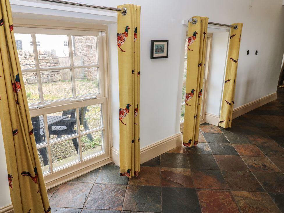 A hallway with windows and curtains at Rainbow Cottage in Kirkby Stephen