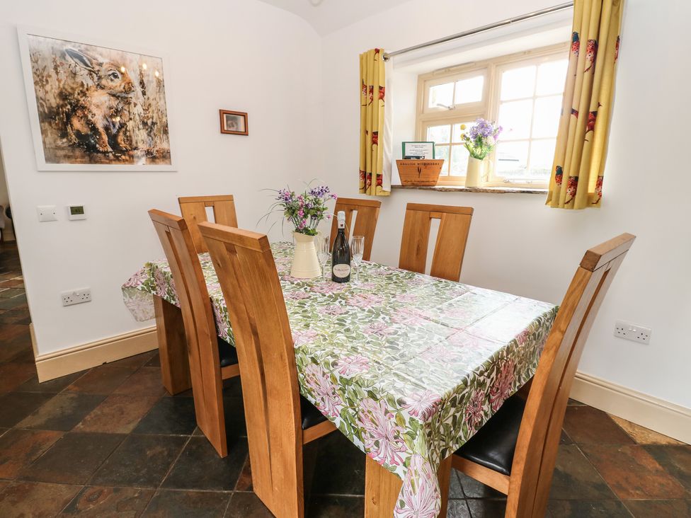 A dining room with a table set for dinner at Rainbow Cottage in Kirkby Stephen