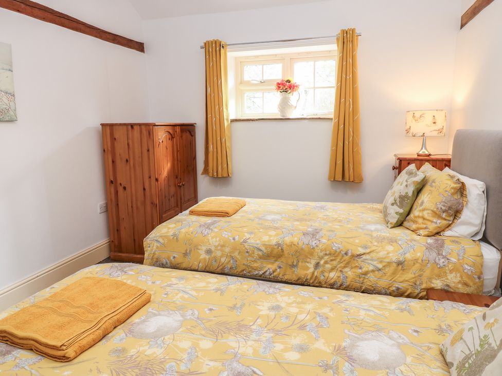 A bedroom with two beds and a window at Rainbow Cottage in Kirkby Stephen
