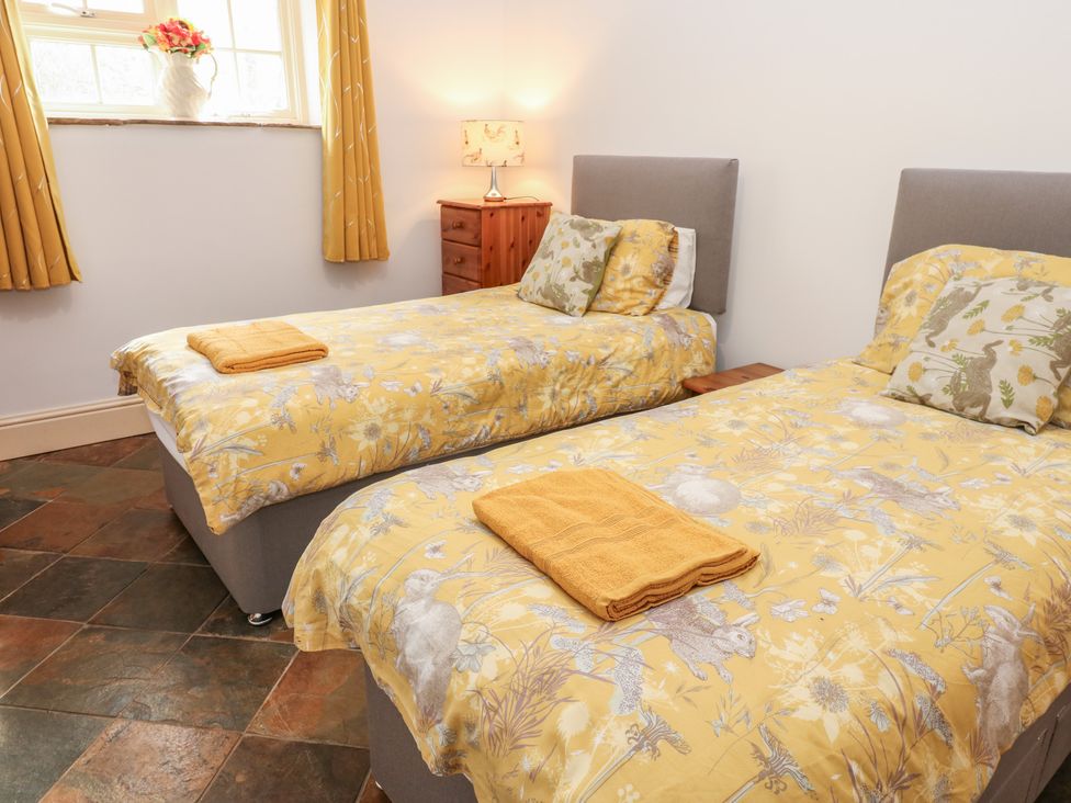 A bedroom with twin beds and a side table at Rainbow Cottage in Kirkby Stephen
