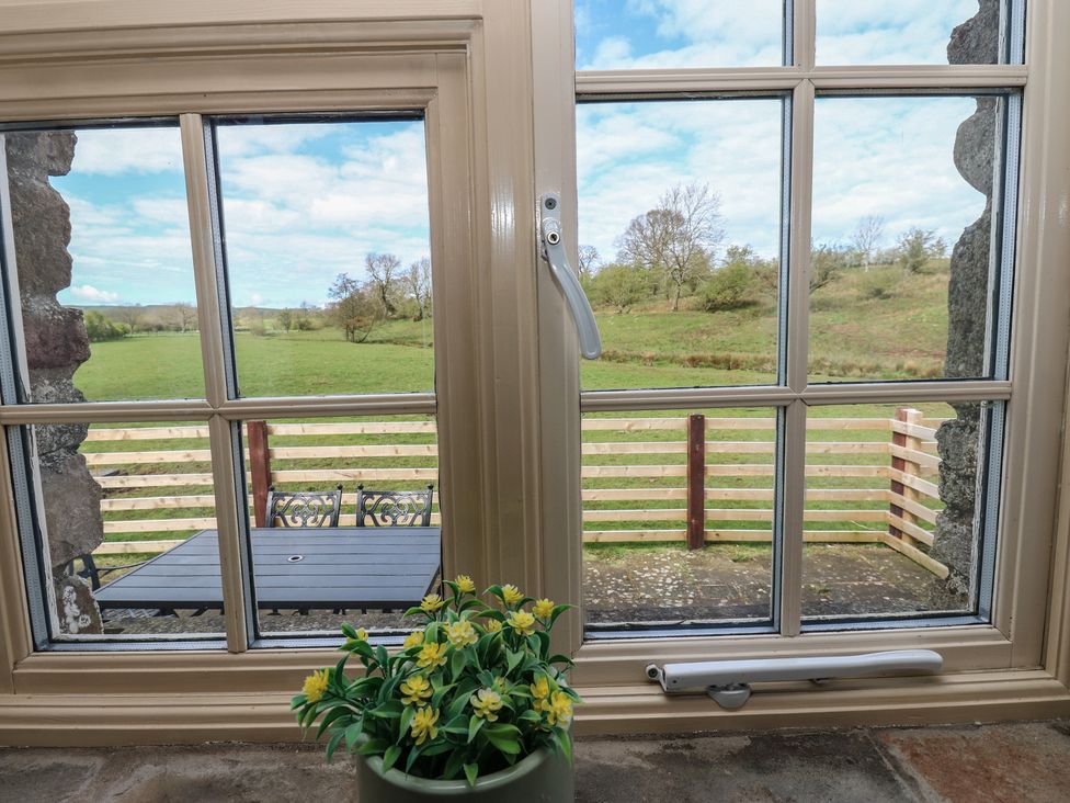 A window view showing a field and table at Rainbow Cottage in Kirkby Stephen