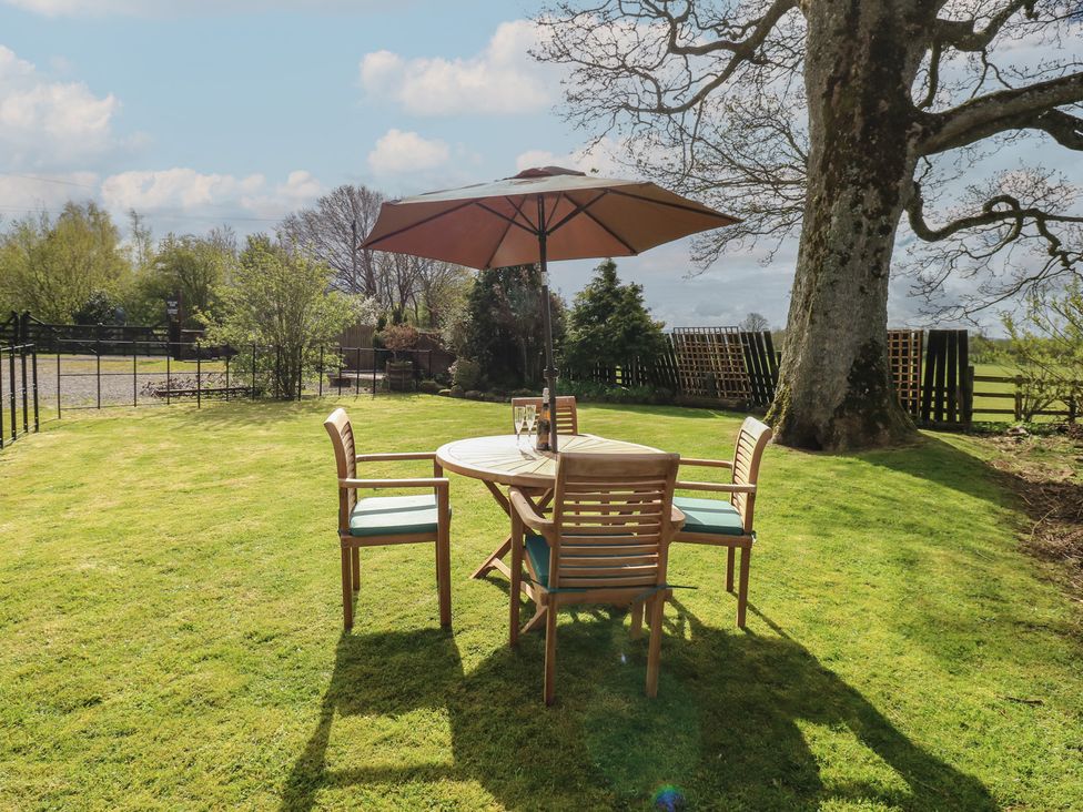 A table and chairs with an umbrella in a garden at Rainbow Cottage Kirkby Stephen