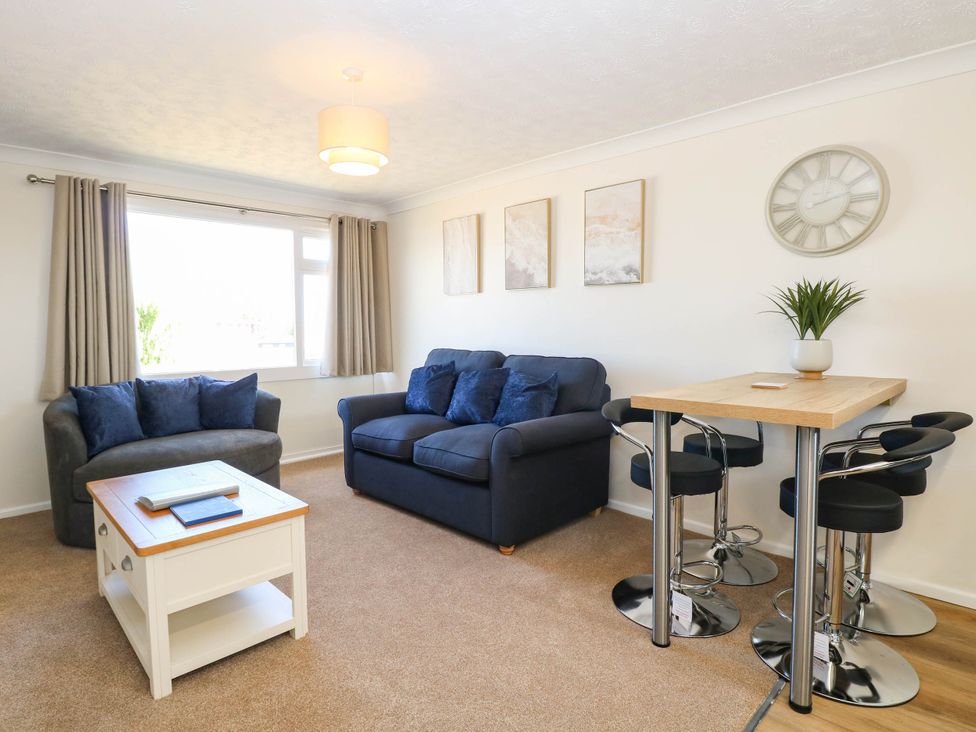 A living room with a sofa, coffee table, and dining table with bar stools at 158 Beach Road Chalet Park