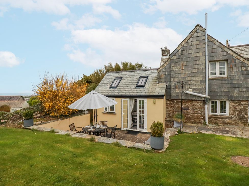 An outdoor seating area with a table and chairs at Ivy Cottage in Trenale near Tintagel