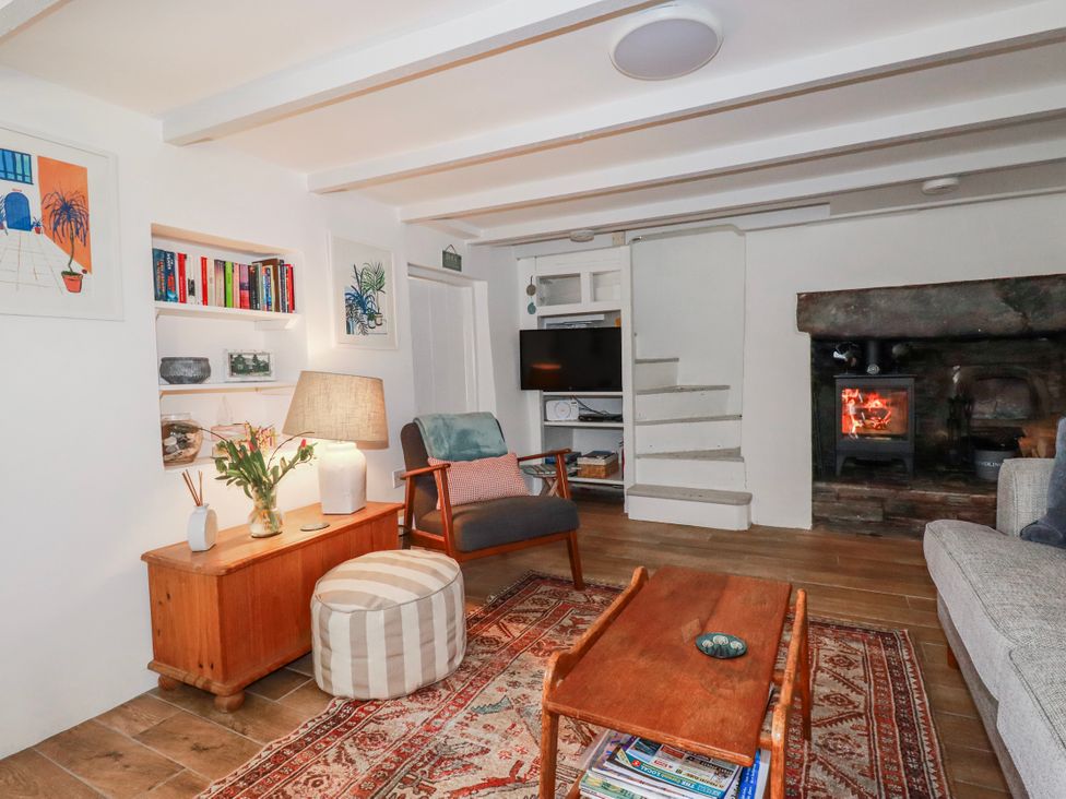 A living room with a lamp, television, and fireplace at Ivy Cottage in Trenale near Tintagel