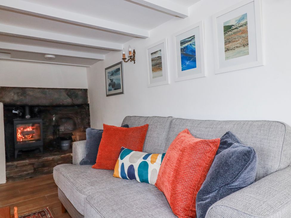 A living room with a sofa and fireplace at Ivy Cottage Trenale near Tintagel