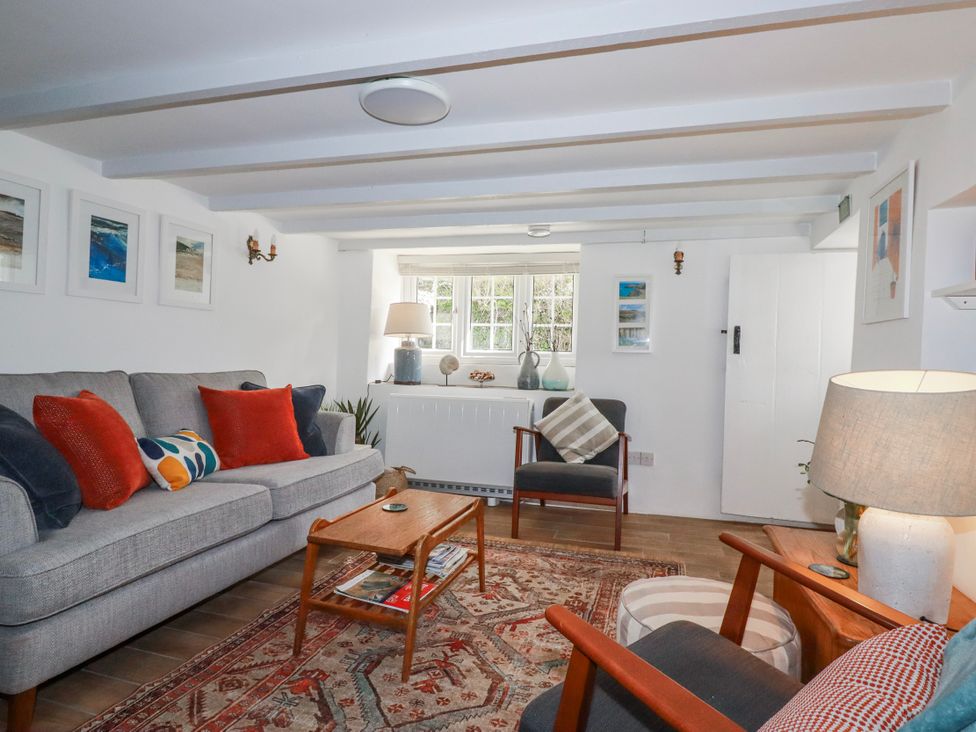 A living room with a sofa, armchair, and coffee table at Ivy Cottage in Trenale near Tintagel