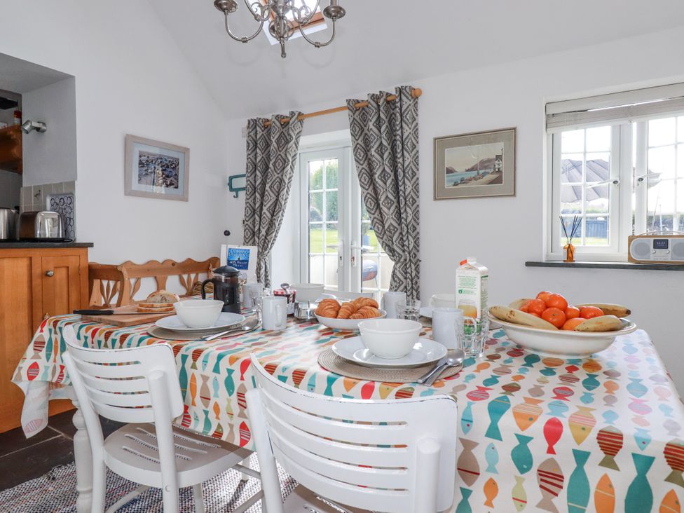 A dining room with a table set for breakfast at Ivy Cottage in Trenale near Tintagel