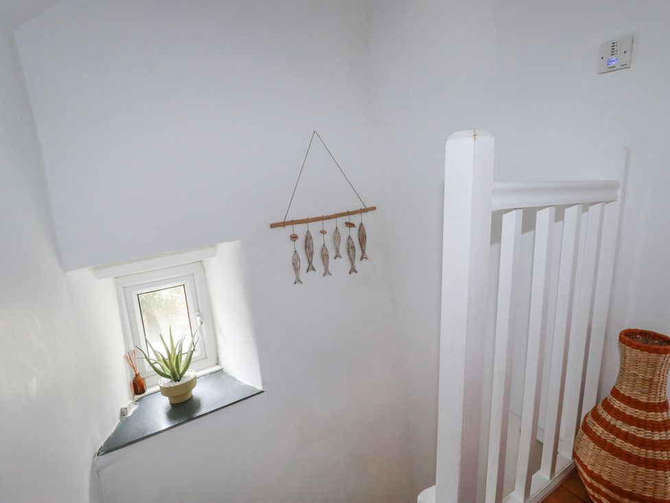 A staircase with a window and potted plant at Ivy Cottage in Trenale near Tintagel