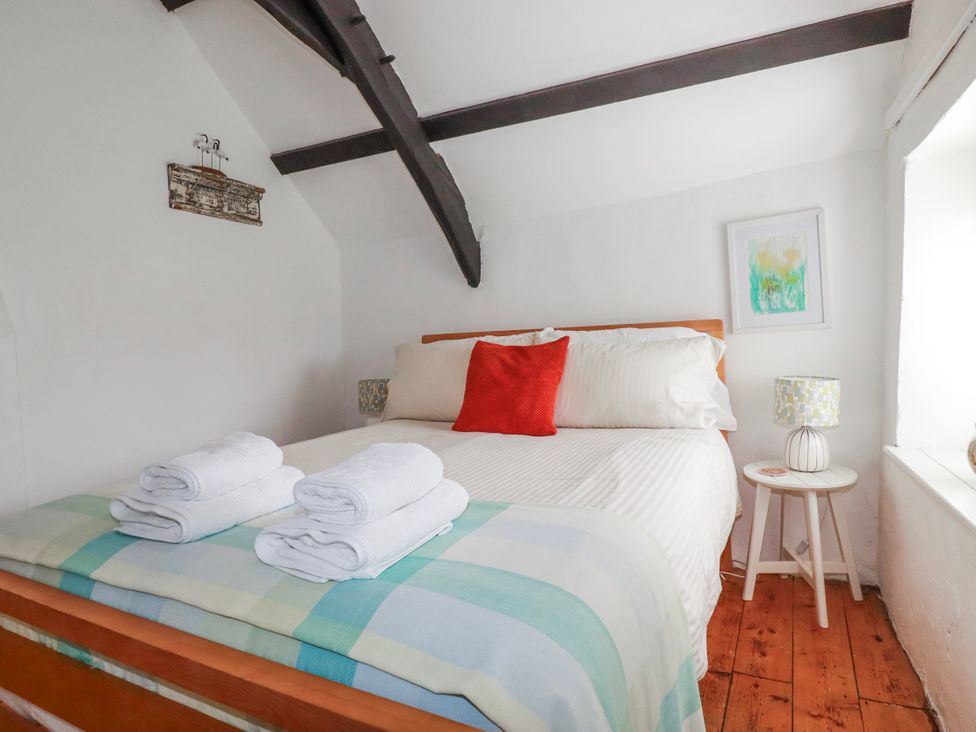 A bedroom with a bed and towels at Ivy Cottage in Trenale near Tintagel