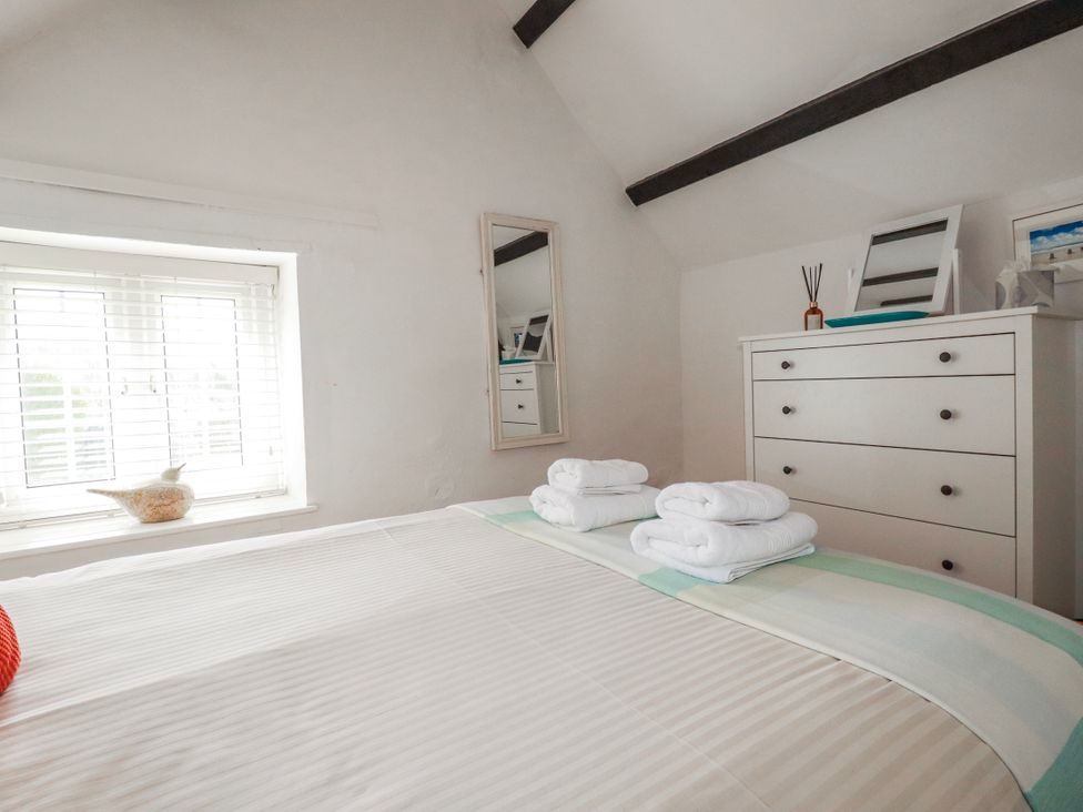 A bedroom with a bed and dresser at Ivy Cottage in Trenale near Tintagel
