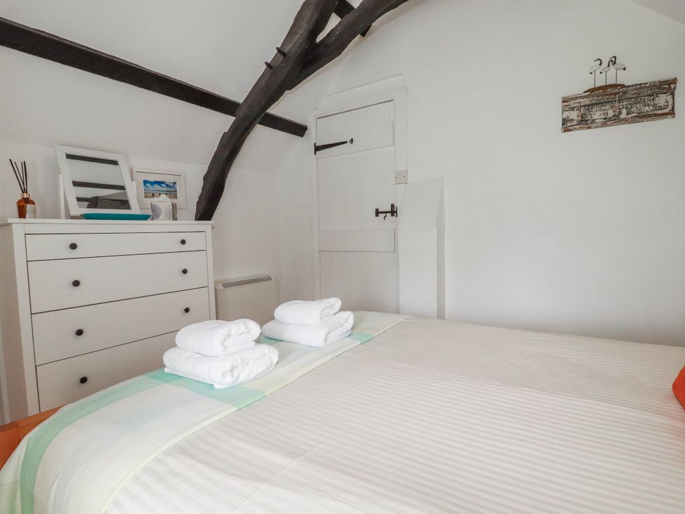 A bedroom with a bed and dresser at Ivy Cottage Trenale near Tintagel