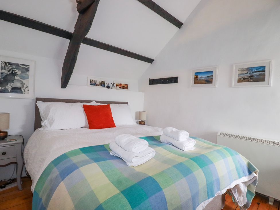 A bedroom with a bed and nightstand at Ivy Cottage Trenale near Tintagel