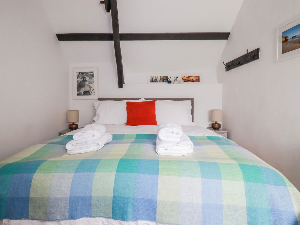 A bedroom with a bed and pillows at Ivy Cottage Trenale near Tintagel