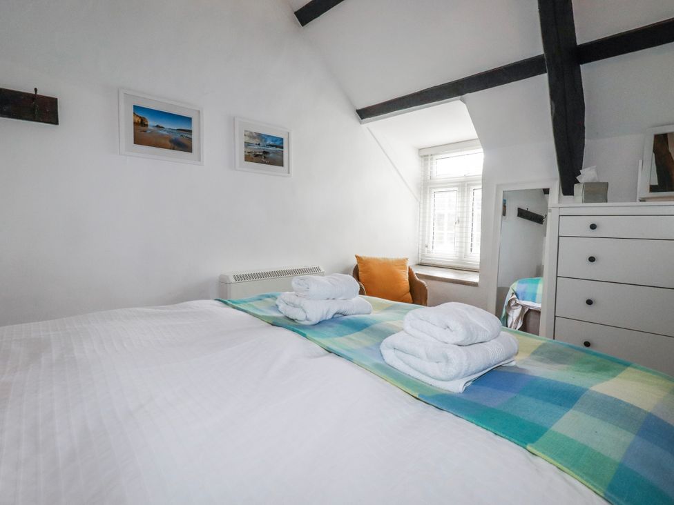A bedroom with a bed and towels on top at Ivy Cottage in Trenale near Tintagel