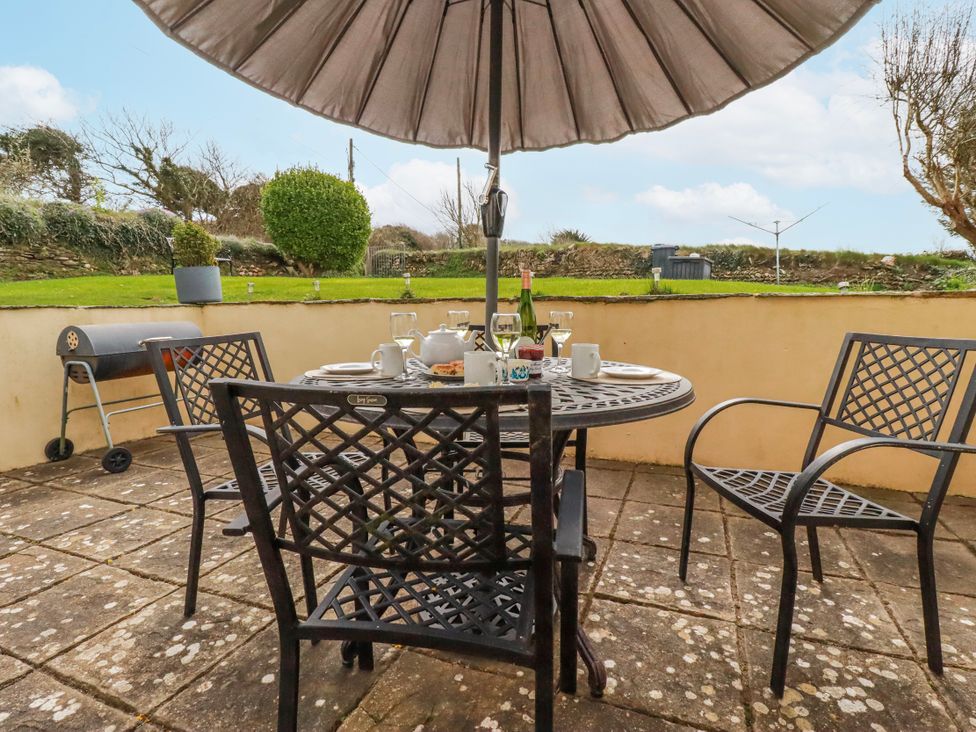 An outdoor dining area with a table and chairs at Ivy Cottage in Trenale near Tintagel