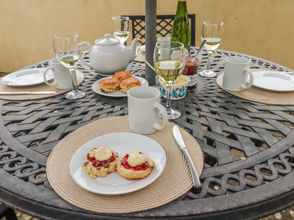 An outdoor dining area with a tea set and plates of scones at Ivy Cottage in Trenale near Tintagel