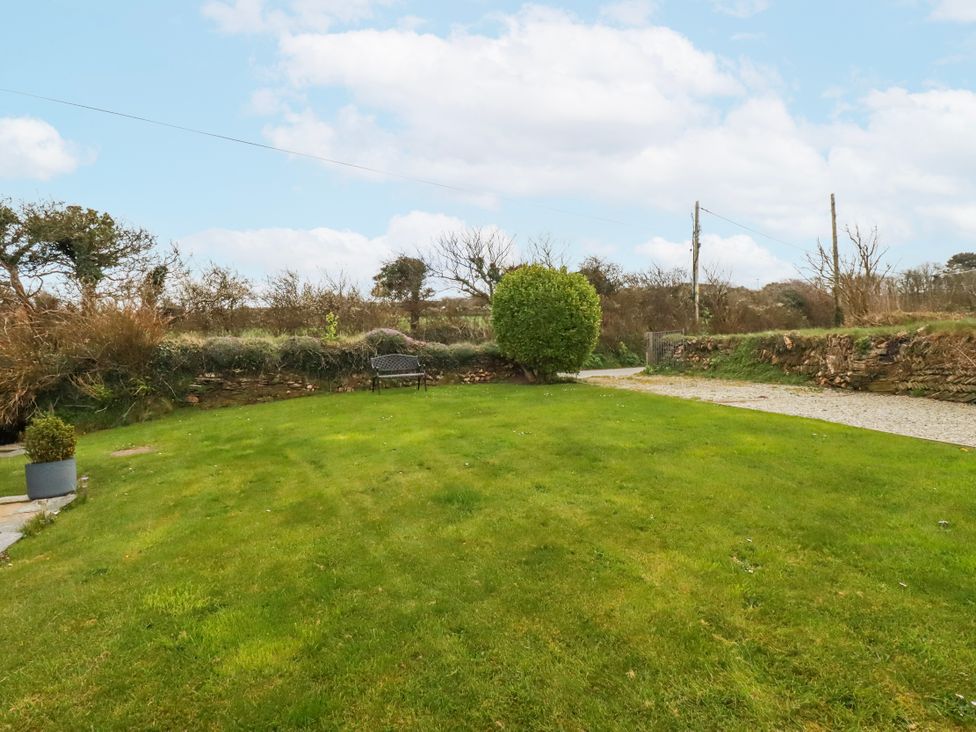 A garden with a bench and green grass at Ivy Cottage in Trenale near Tintagel