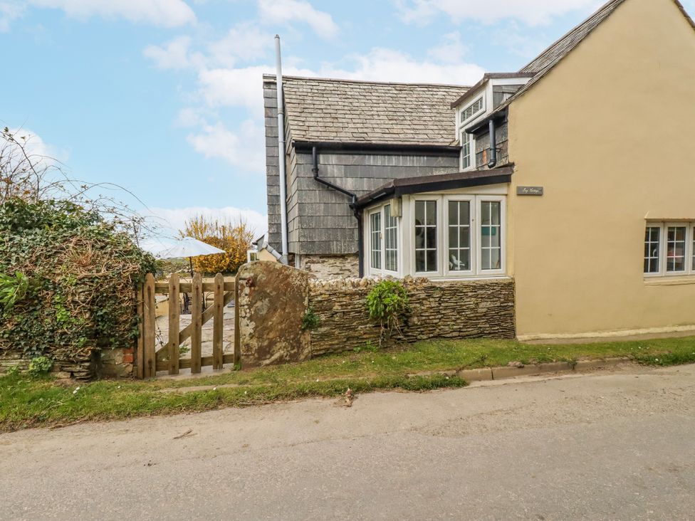 An exterior view of a house with a gate and stone wall at Ivy Cottage in Trenale near Tintagel