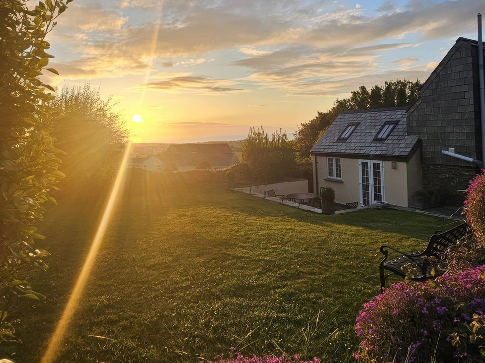 A sunset over a garden with a house at Ivy Cottage, Trenale near Tintagel