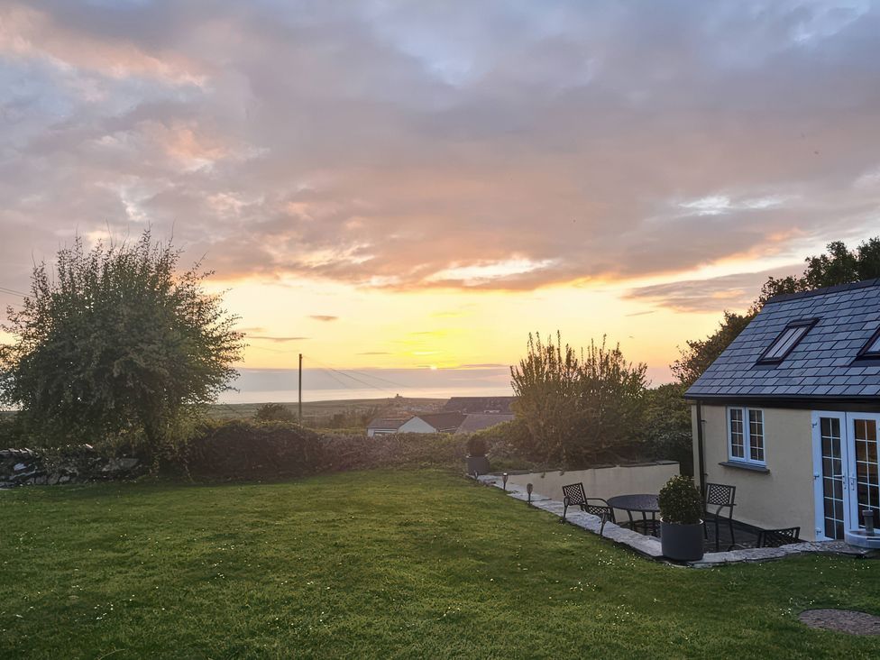 A garden with a house and table at Ivy Cottage in Trenale near Tintagel