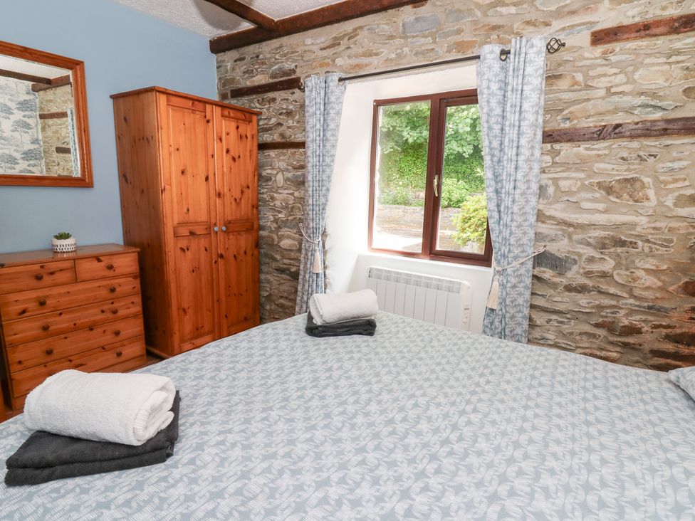 A bedroom with a bed and wooden furniture at The Stable in Llandysul