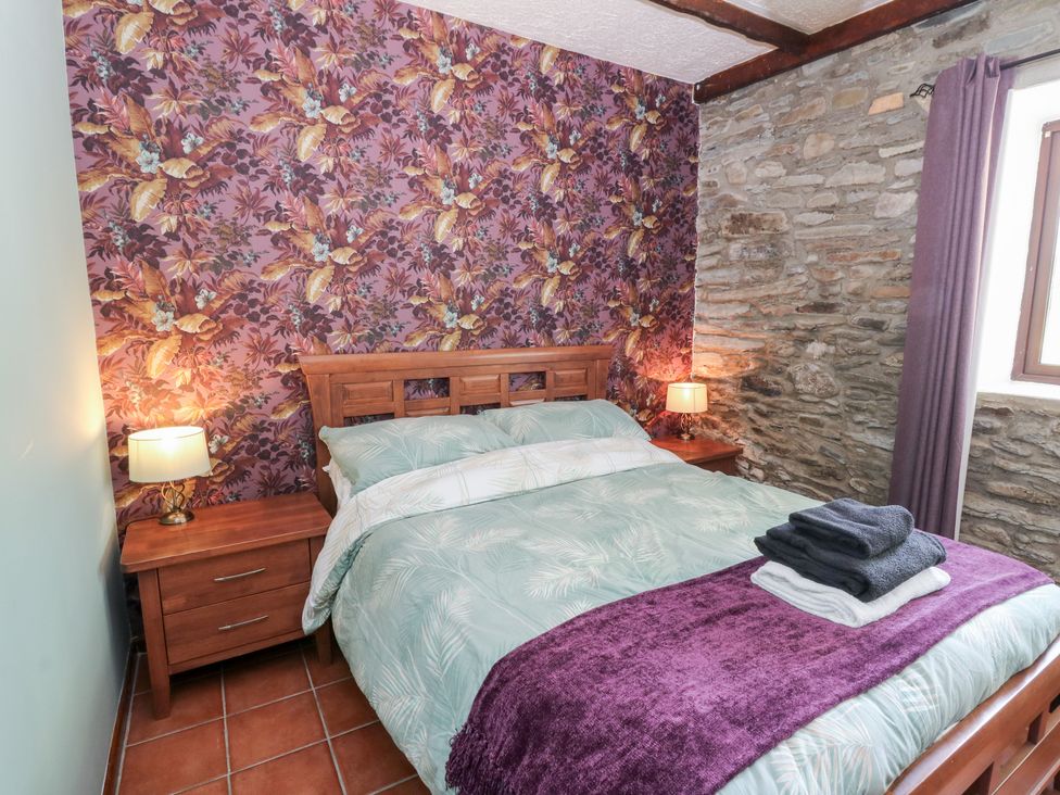 A bedroom with a bed and nightstand at The Stable in Llandysul