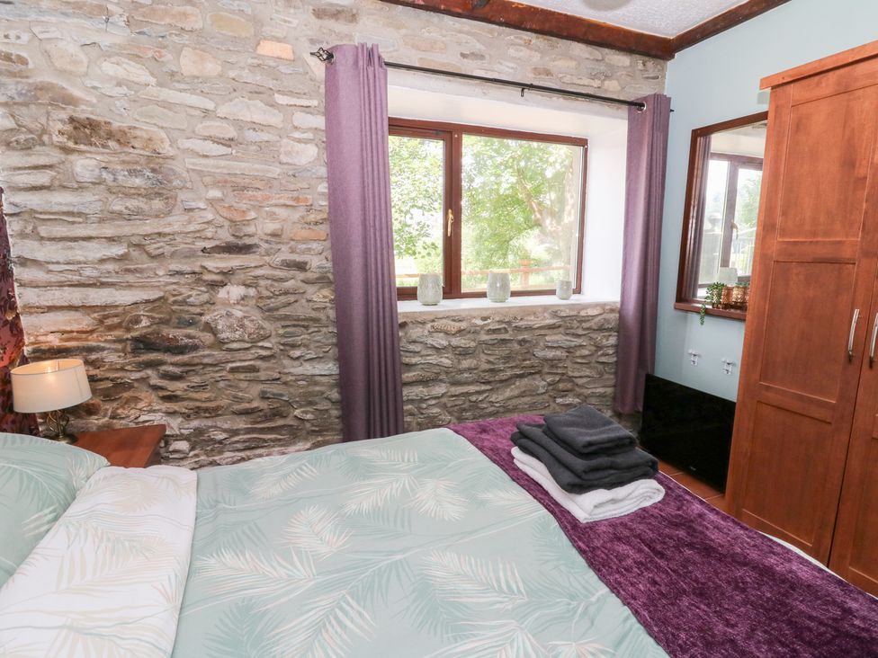 A bedroom with a bed and window at The Stable in Llandysul