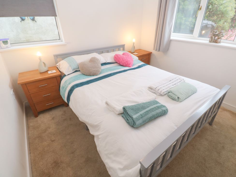 A bedroom with a bed and nightstands at Sandyfeet Roskear Croft near Camborne